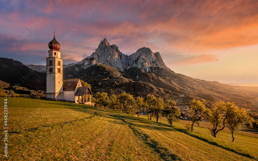 Seis am Schlern, Italy - Beautiful sunset and idyllic mountain scenery in the Italian Dolomites with St. Valentin Church and famous Mount Sciliar with colorful clouds and warm sunlight at South Tyrol