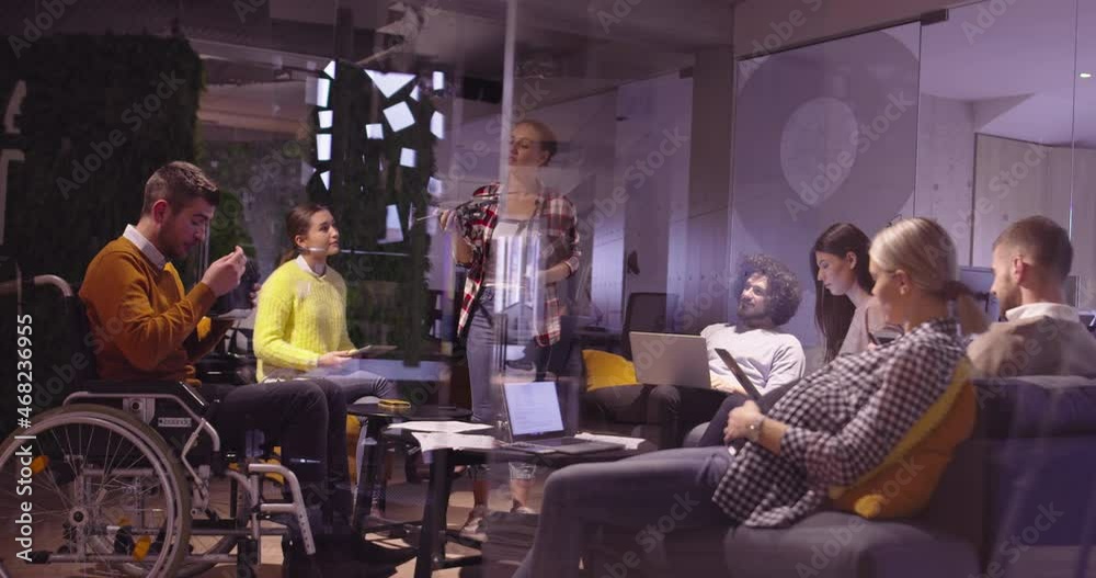 Disabled businessman in a wheelchair at work in modern open space coworking office on team meeting using virtual reality goggles and drone simulation. Effective teamwork in a startup business.