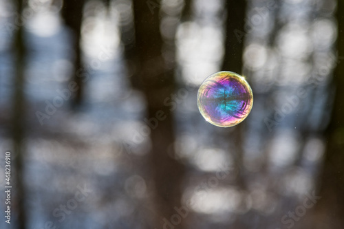 Farbenspiel fliegender Seifenblasen über Schnee und bei Sonnenschein