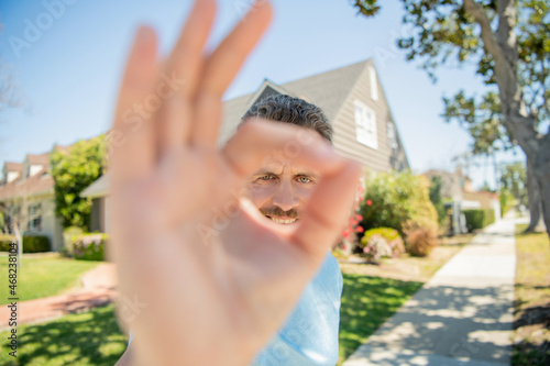 ok gesture of mature man standing outdoor at house, selective focus, businessman