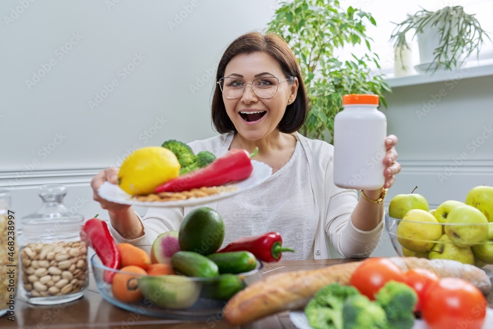 Woman nutritionist pointing at the camera a plate with a set of healthy food and a jar of food additives Woman nutritionist pointing at the camera a plate with a set of healthy food and a jar of food additives