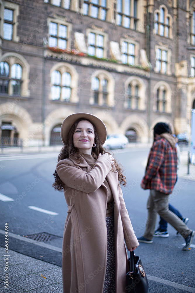 Pretty woman with curly hair in old town dressed in autumn coat and a hat Pretty woman with curly hair in old town dressed in autumn coat and a hat