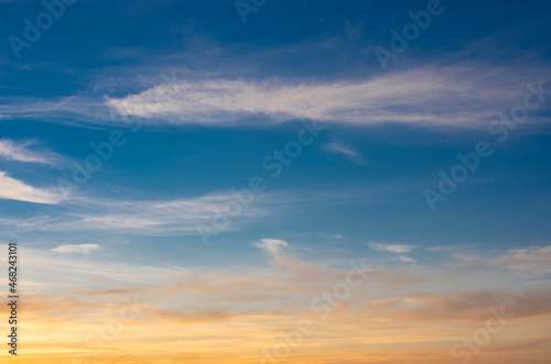Dawn sky in the form of stripes of blue and orange with cirrus clouds.