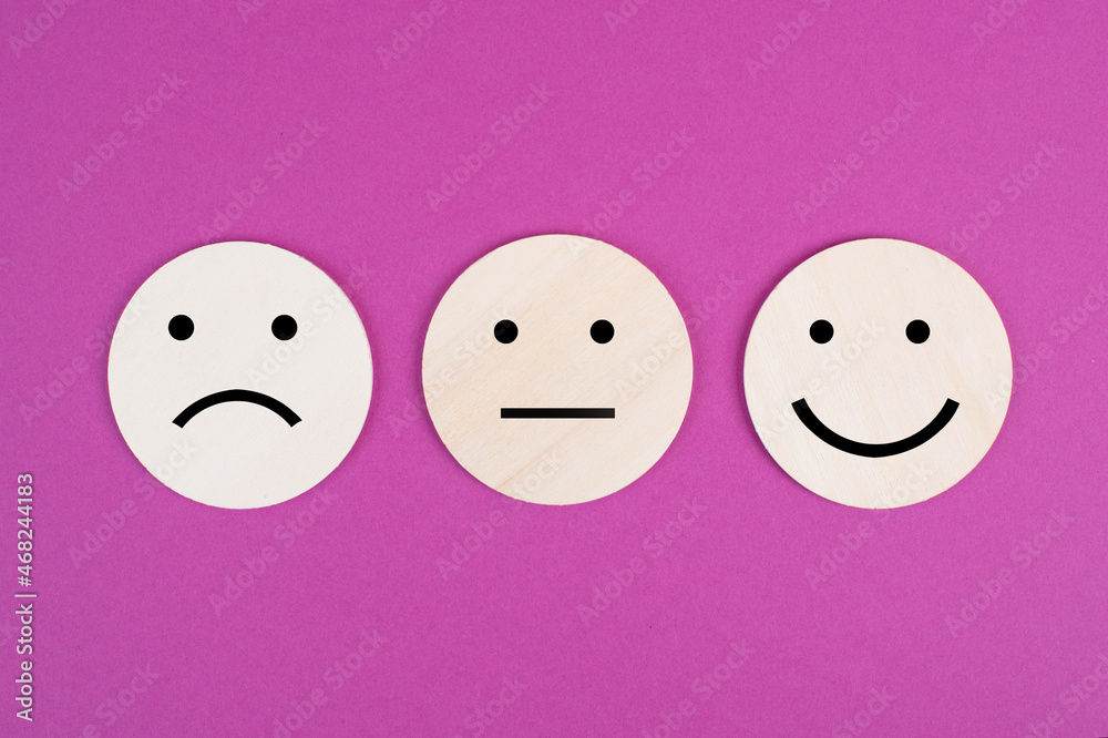 Three faces, smiling, sad in different colors on a pink background, copy space, rating, communication, customer feedback Three faces, smiling, sad in different colors on a pink background, copy space, rating, communication, customer feedback