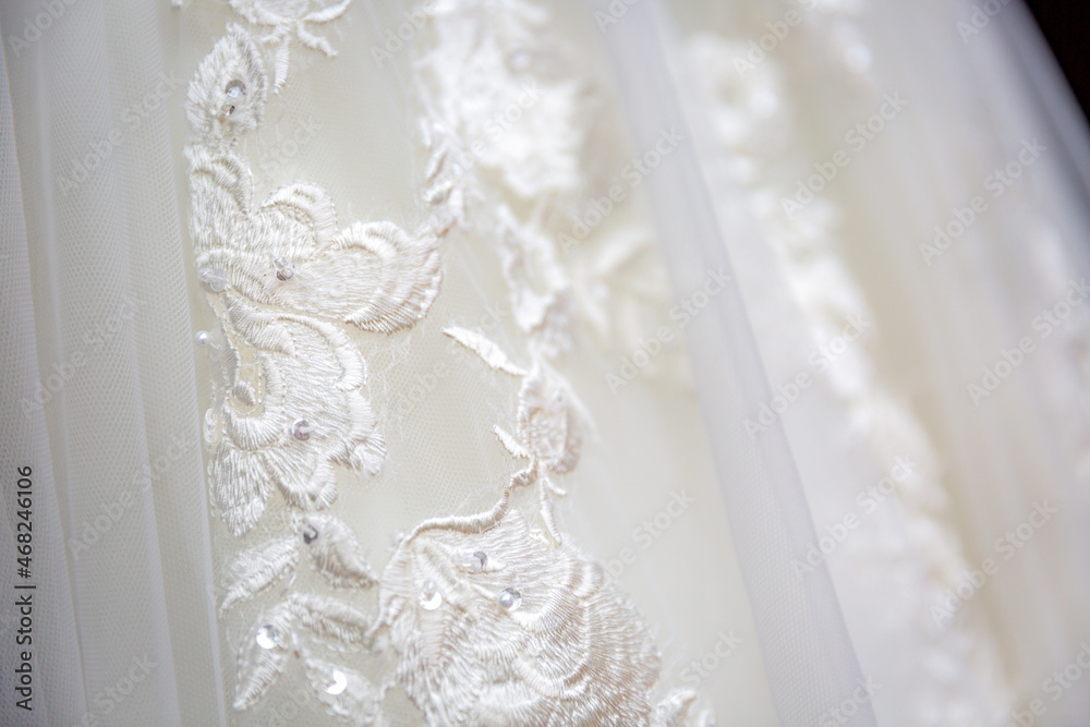 Close up view white flowers pattern on white wedding dress. Classic wedding dress styles concept Close up view white flowers pattern on white wedding dress. Classic wedding dress styles concept