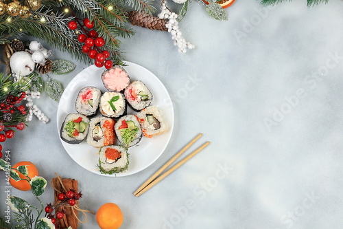 Herringbone of fresh sushi rolls with sauce on a light background with holiday decorations, christmas new year food, traditional japanese cuisine,banner for shop advertisement or invitation, 