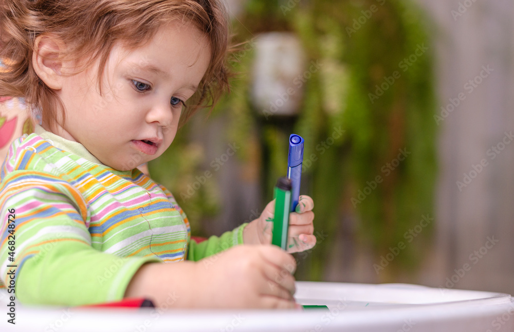 A little girl draws with a marker A little girl draws with a marker