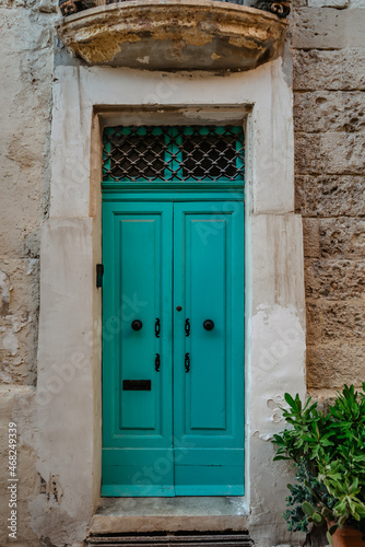 Malta is home to amazingly unique doors.Traditional colorful Maltese door in Valletta.Front door to house from Malta.Blue turquoise wooden door and stone facade.Maltese vintage apartment building. © Eva