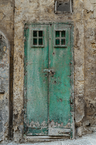 Malta is home to amazingly unique doors.Traditional old Maltese door in Valletta.Front door to house from Malta.Blue green antique wooden door and stone facade.Maltese vintage apartment building. © Eva
