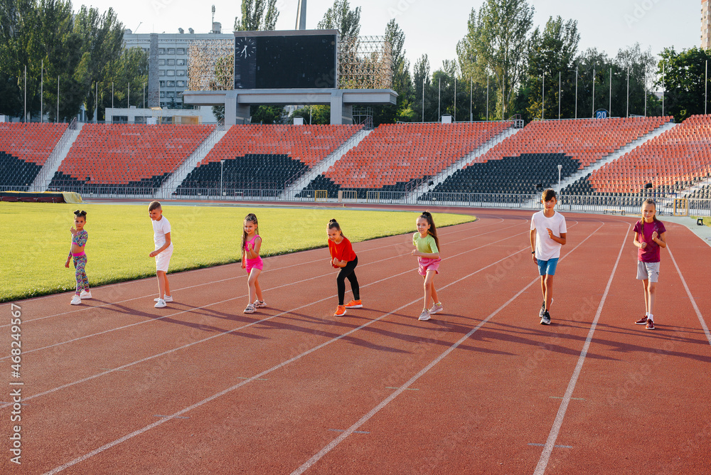 Fototapeta premium A large group of children, boys and girls, run and play sports at the stadium during sunset. A healthy lifestyle.