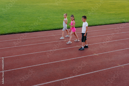 A large group of children, boys and girls, run and play sports at the stadium during sunset. A healthy lifestyle.