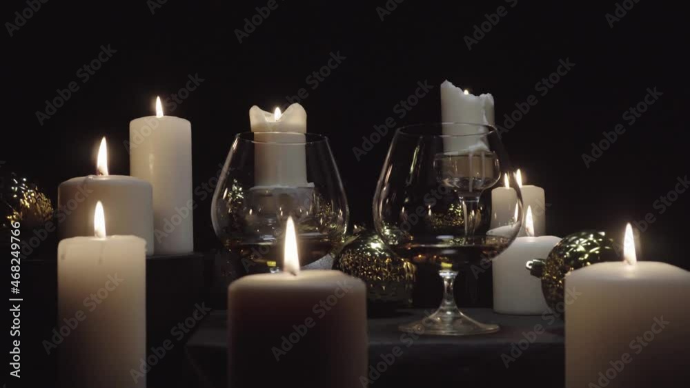 Glasses with brandy on the background of burning candles and Christmas and new year decorations, dolly shot Glasses with brandy on the background of burning candles and Christmas and new year decorations, dolly shot