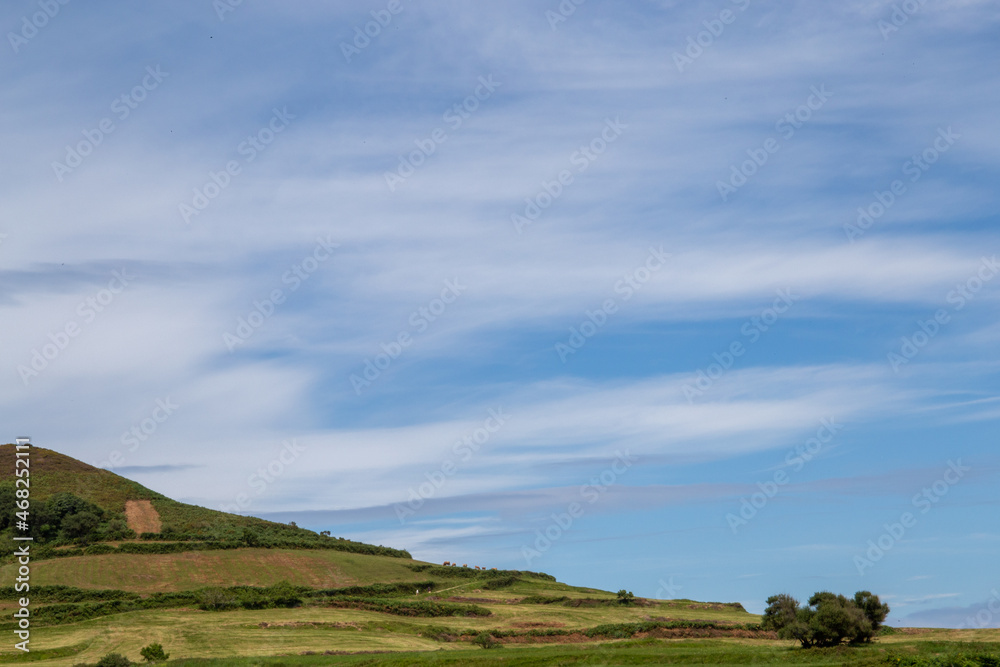 Green grassy slope with blue sky and some clouds