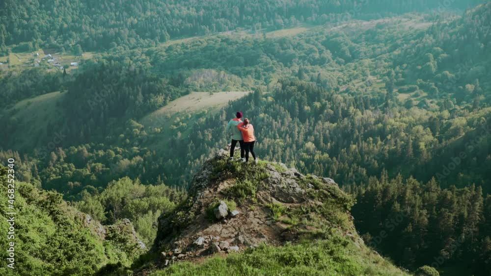 A young woman approaches a man to a cliff in a mountainous area. Travel A young woman approaches a man to a cliff in a mountainous area. Travel