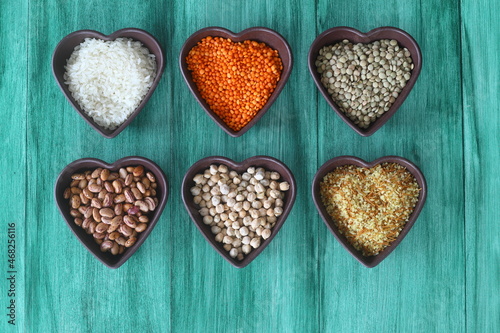 Different type of raw dry legumes composition. White Rice, lentils, red lentils, chickpeas and kidney beans. Mix organic legume concept. With Heart shape bowl. 