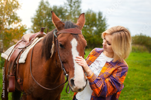 Beautiful young blond woman with a horse, portrait.