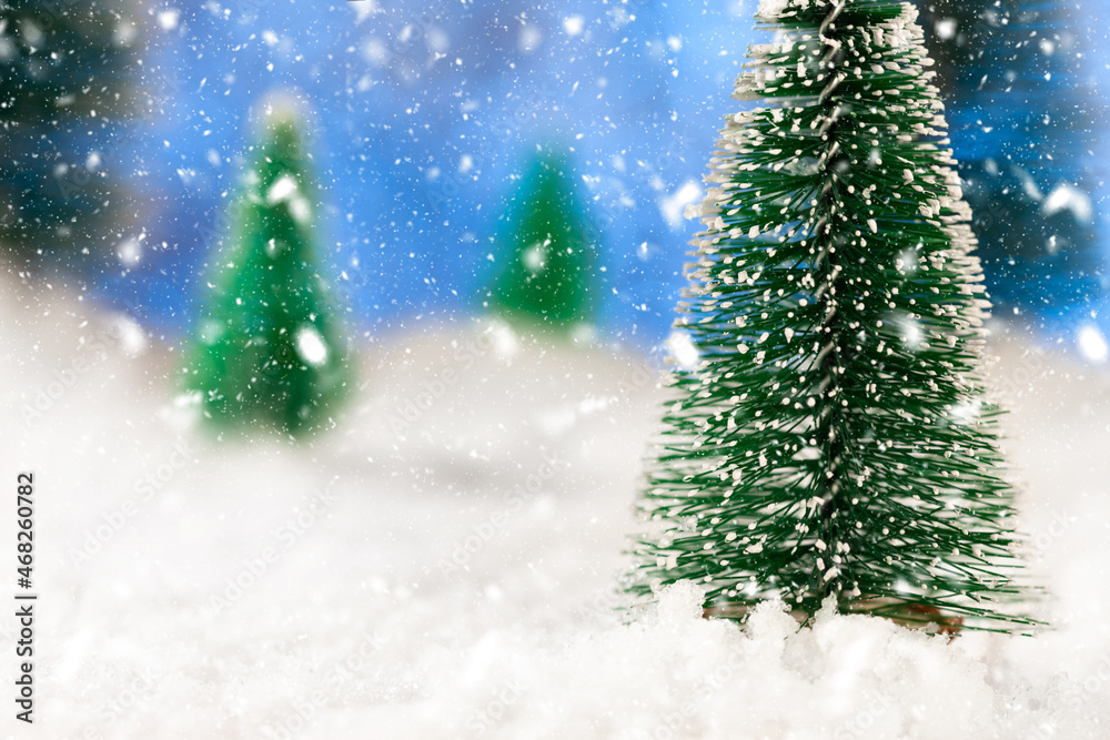 New year greeting card. Little toy firs in the snow. Snowing