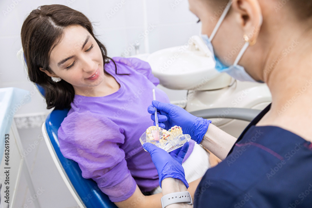 Fototapeta premium Dentistry concept. Professional dental services and modern equipment without pain. The doctor demonstrates to the patient how to properly brush the teeth
