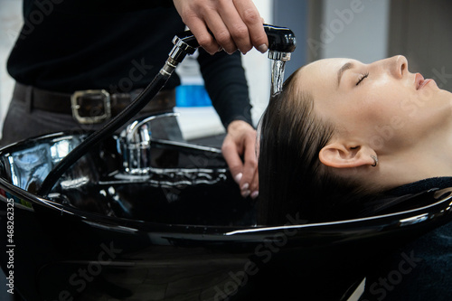 Master woman hairdresser gently washes the girl's hair with shampoo and conditioner before styling in a beauty salon.