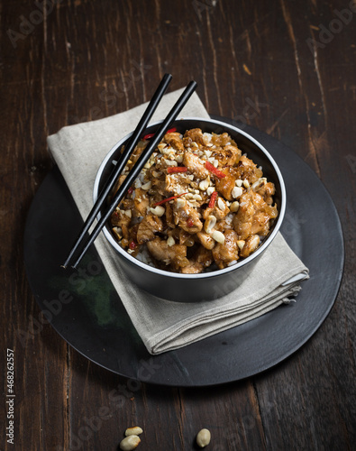 chinese dish. Kung pao, rice with chicken fillet in sauce. Close-up on a dark wooden background, vertical