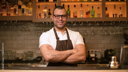 portrait of a confident smiling bartender at the bar in a restaurant with a tattoos on his hands