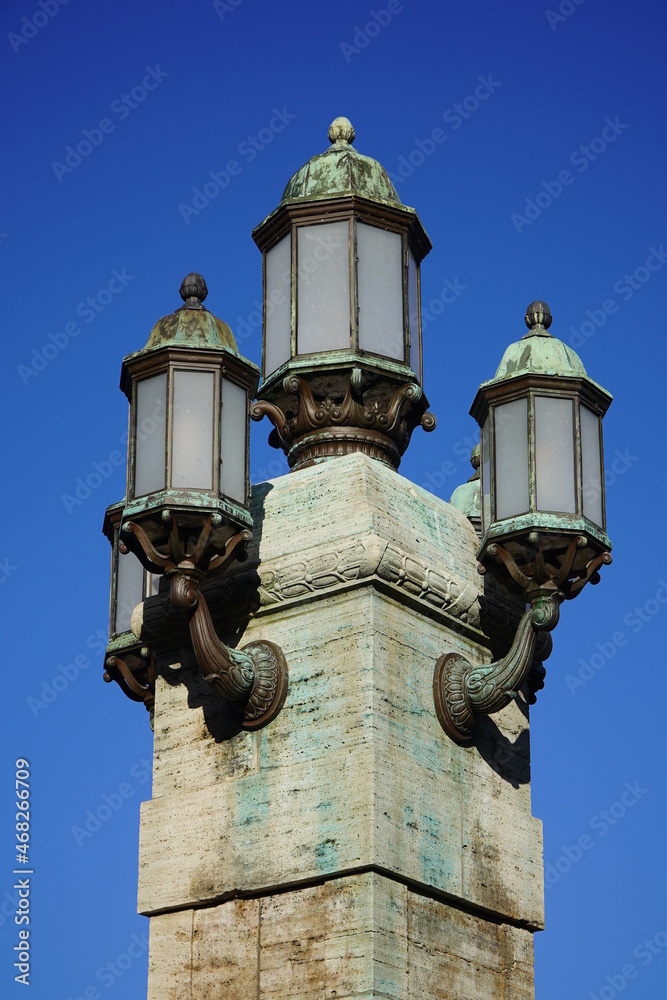 Vintage, old street lamps in classic style, made of metal with corrosion of copper material, glass and on a brick base. Hannover, Trammplatz, Germany