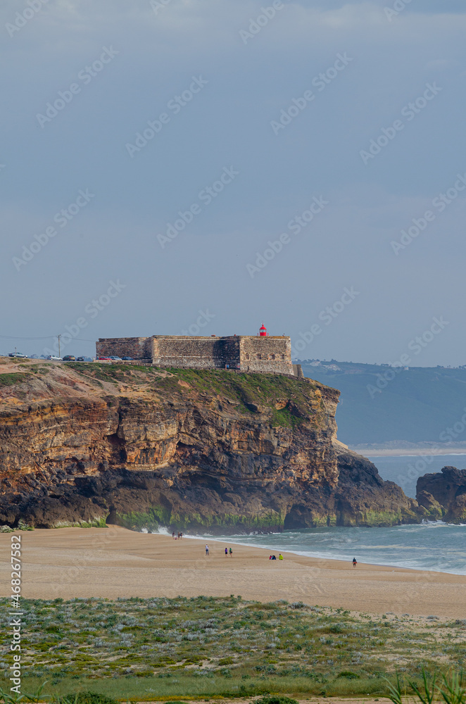 Praia do Norte beach, cliffs and Nazaré lighthouse cape. Portugal.