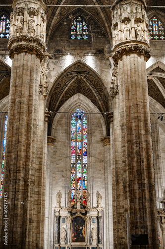 Colored stained glass windows against the huge carved marble columns of the Duomo. Italy  Milan