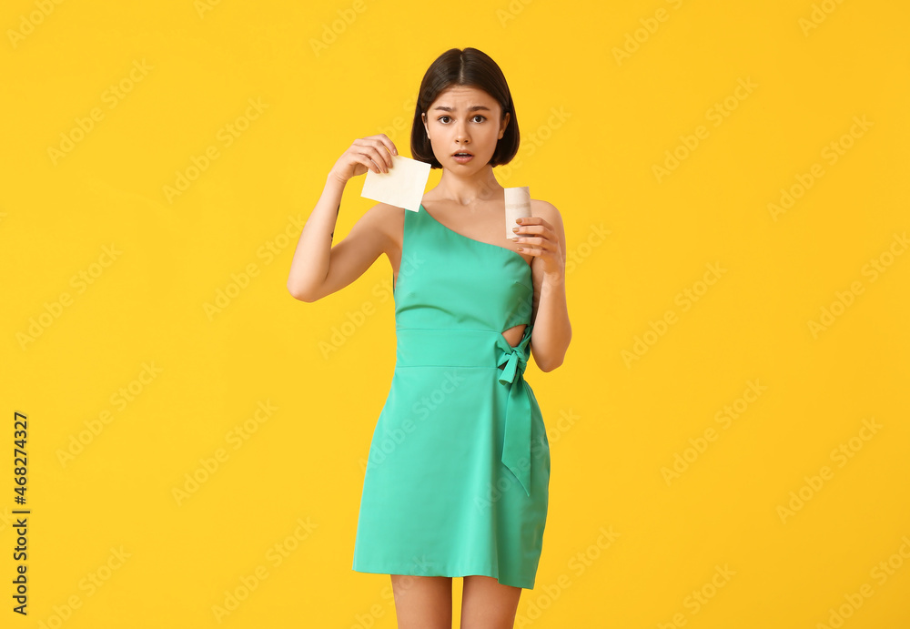 Sad young woman out of toilet paper on color background Sad young woman out of toilet paper on color background