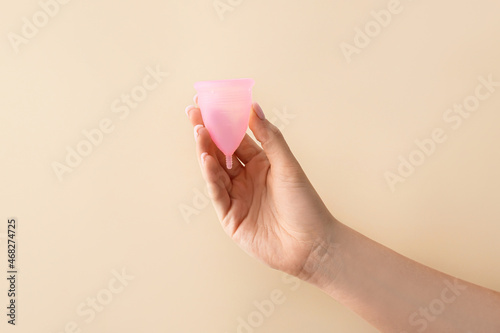 Female hand with menstrual cup on color background
