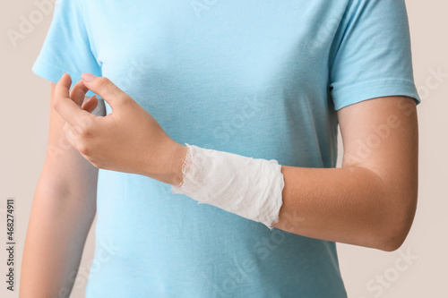 Woman with bandaged hand on color background, closeup