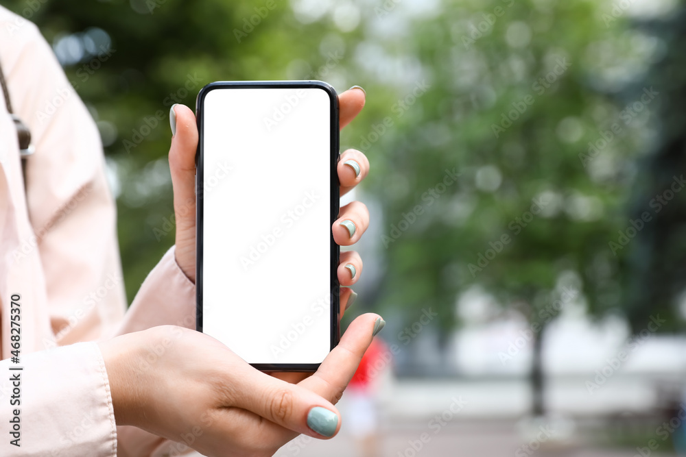 Woman holding mobile phone on city street, closeup