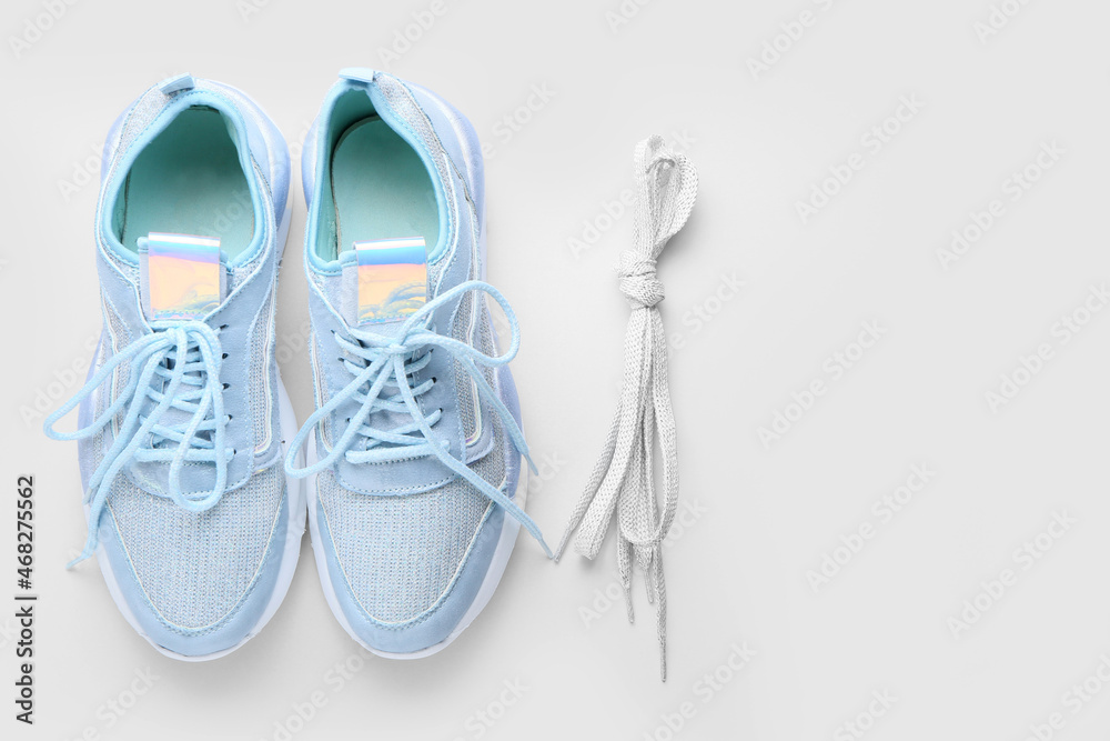 Sportive shoes and laces tied in knot on white background