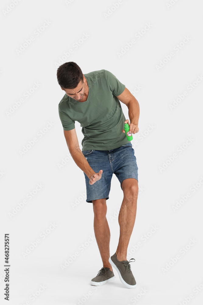 Young man with mosquito repellent on light background Young man with mosquito repellent on light background