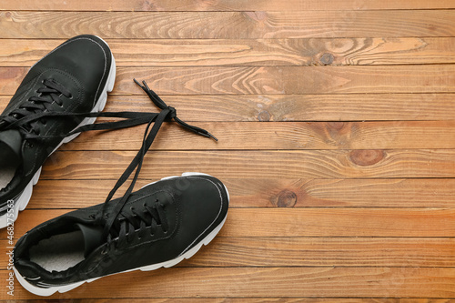 Pair of sportive shoes with laces tied in knot on wooden background, closeup