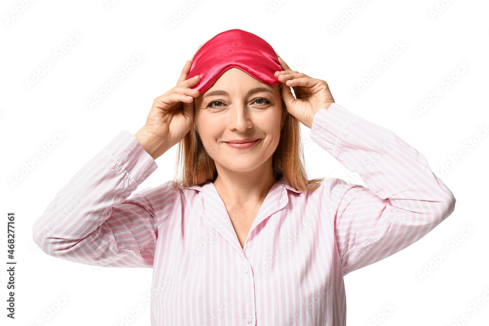 Happy mature woman in pajamas and with sleeping mask on white background