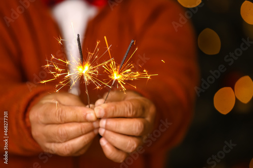 Mature man with Christmas sparklers at home, closeup
