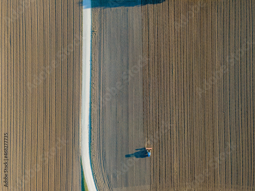 Aerial view of a tractor working in an agricultural field at sunset near Aquileia, Udine, Friuli Venezia Giulia, Italy.