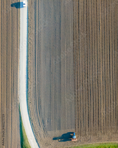 Aerial view of a tractor working in an agricultural field at sunset near Aquileia, Udine, Friuli Venezia Giulia, Italy.