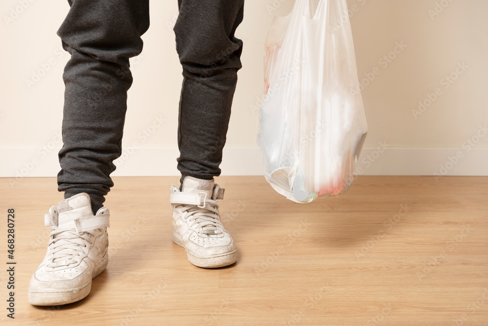 shopping bag carried by a person with a tracksuit and white sneakers shopping bag carried by a person with a tracksuit and white sneakers