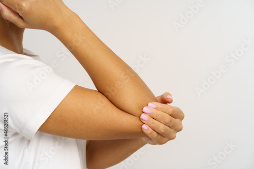 Black female suffering from pain in elbow massaging injured hand. Cropped image of unrecognizable african american woman with hurting arm, injury or bone fracture. Rheumatism or inflammation concept