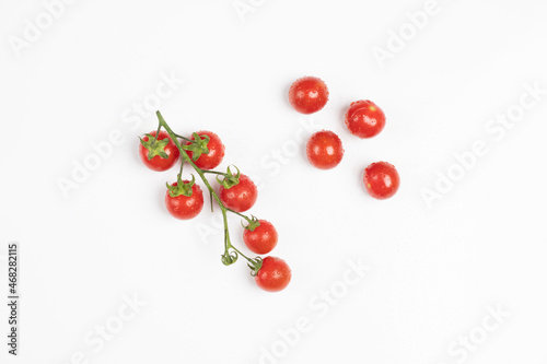 Pomodorini ciliegini freschi attaccati al ramo e sparsi su sfondo bianco / Fresh cherry tomatoes attached to the branch and scattered over white background photo