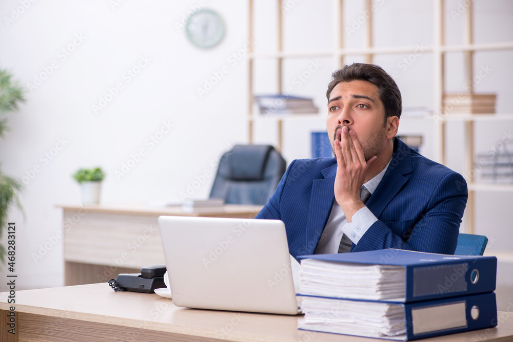 Young male employee and too much work in the office Young male employee and too much work in the office