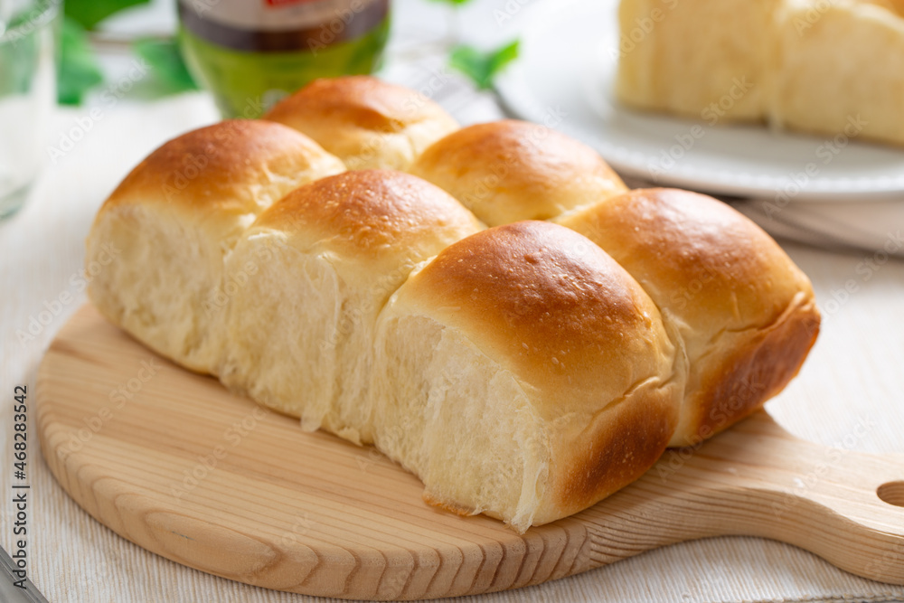 Freshly baked golden brown dinner rolls bread served on wooden board