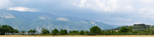 Fields and forests of Bulgaria before the rain. Panorama. Thunderhead covers the Balkans. Downpour is approaching agricultural land.