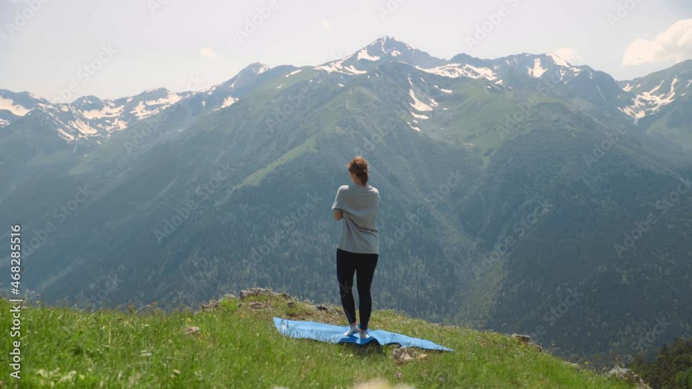 A young woman does yoga on the tops of mountains. Sports tourism A young woman does yoga on the tops of mountains. Sports tourism