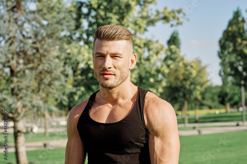 a man in a black t-shirt in a nature park with dumbbells workout