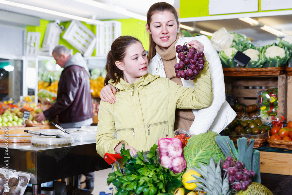 Portrait of laughing mother with daughter shopping together in fruit market