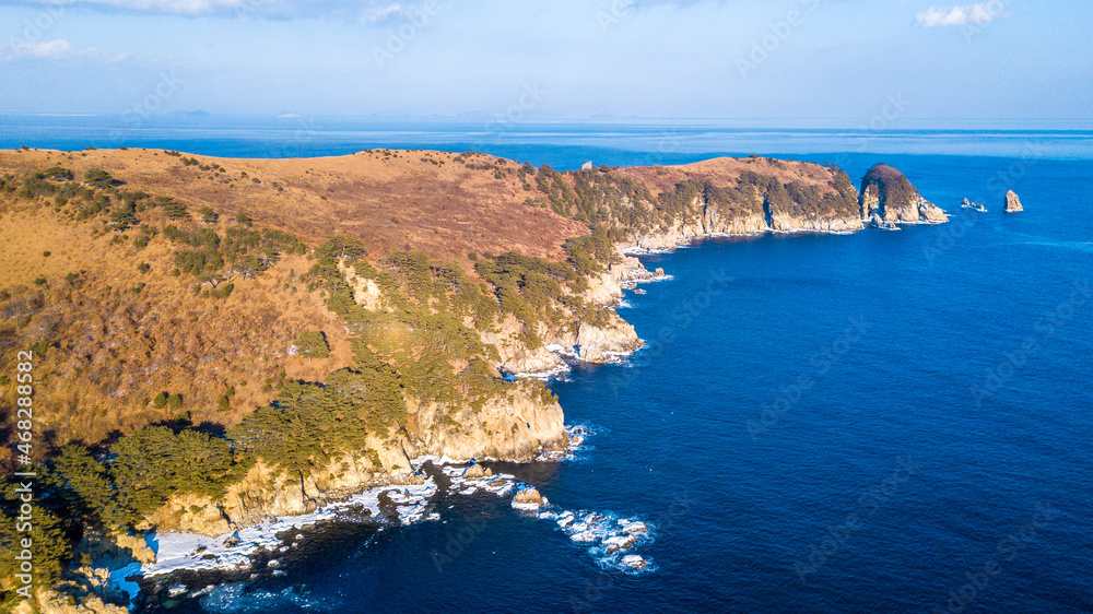 Far Eastern Marine Reserve in winter. Beautiful landscape of the Sea of Japan and the winter coast. Rocky coast, striped with conifers. View from above.