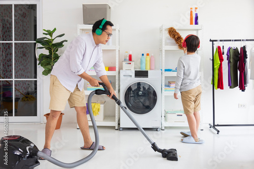 Картината върху платно Asian father and son help each other to clean the house using vacuum machine for